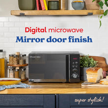 Digital microwave with mirror door finish on a kitchen counter, surrounded by kitchen items.