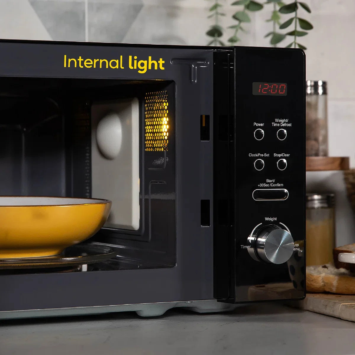 Black microwave oven with a yellow bowl inside, labeled 'Internal light', on a kitchen counter.