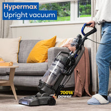 Person using a Hypermax upright vacuum cleaner in a living room.